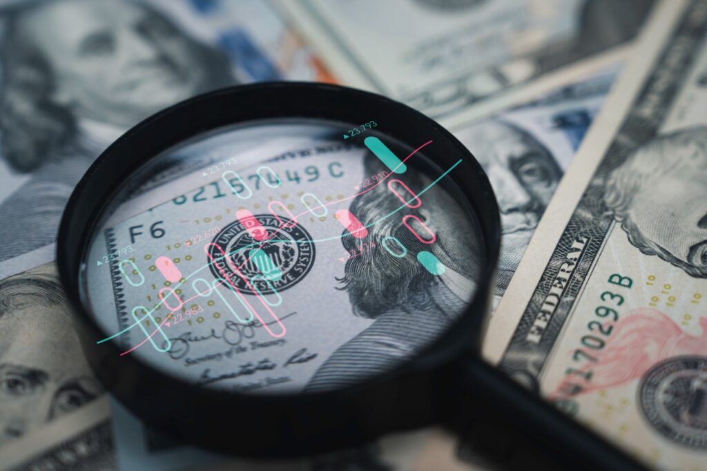 Stock market chart inside magnifier glass on USD banknote image.