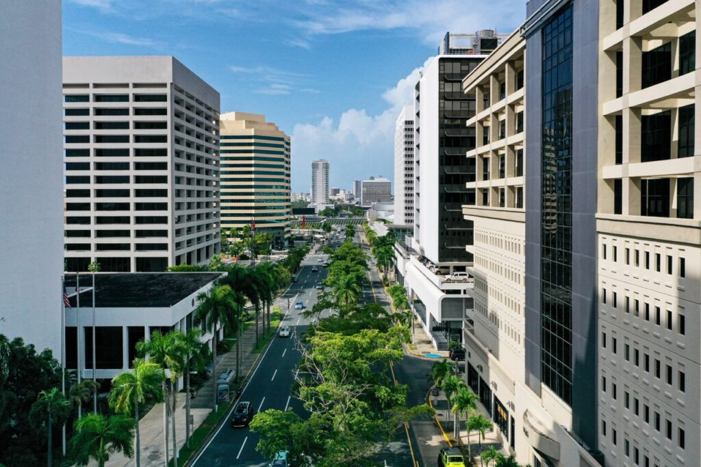 Bird’s-eye view of Milla de Oro in San Juan, Puerto Rico, showcasing modern office buildings and lush green palm trees lining the road.