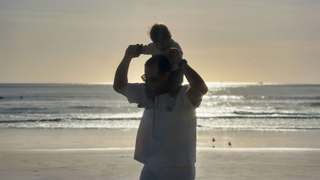 onathan Soto, founder of iTerra Solutions, walks along a Puerto Rico beach at sunset with his child on his shoulders.